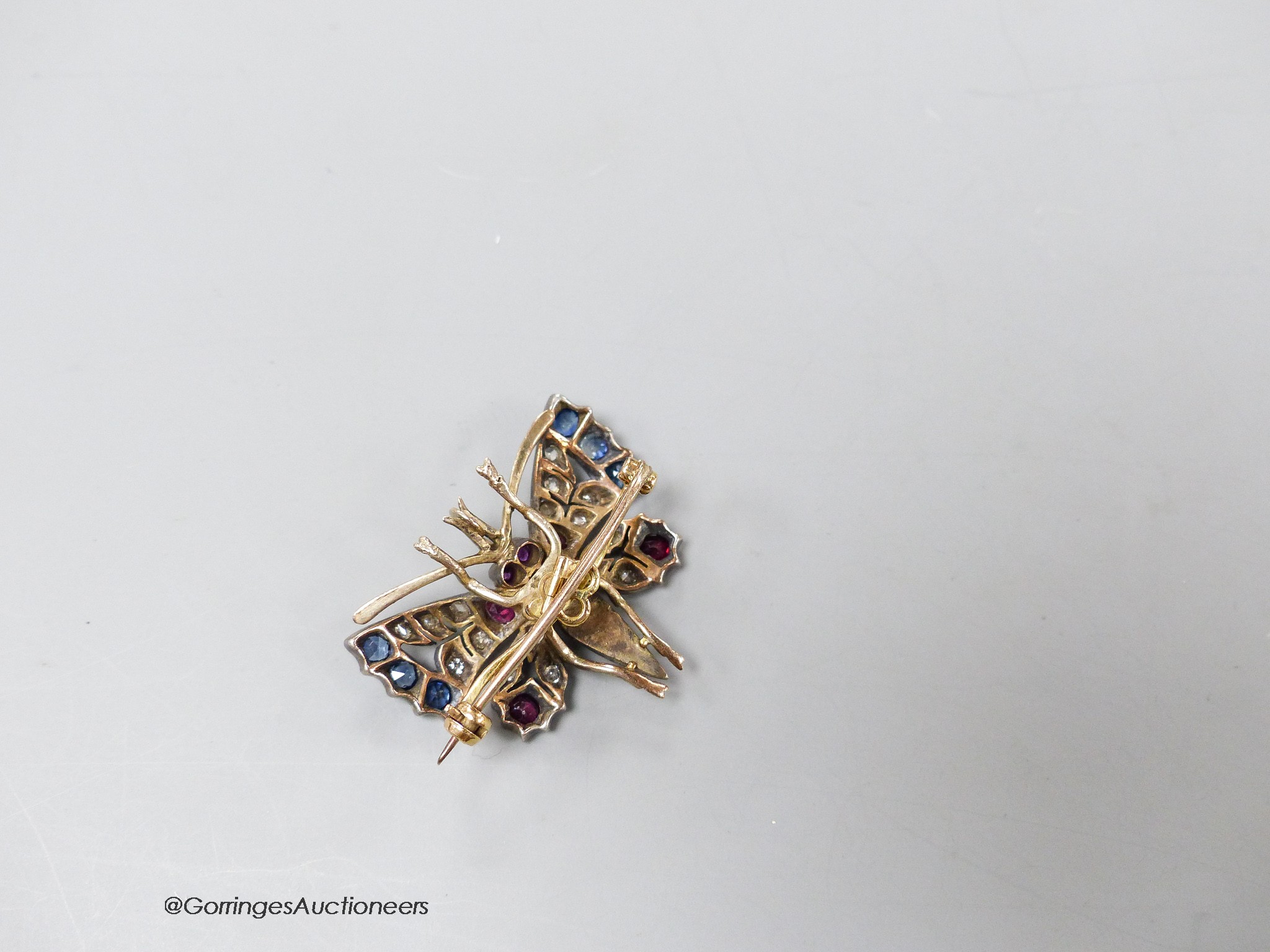 An Edwardian yellow and white metal, ruby, sapphire, diamond and split pearl set butterfly pendant brooch, 32mm, gross 7.9 grams.